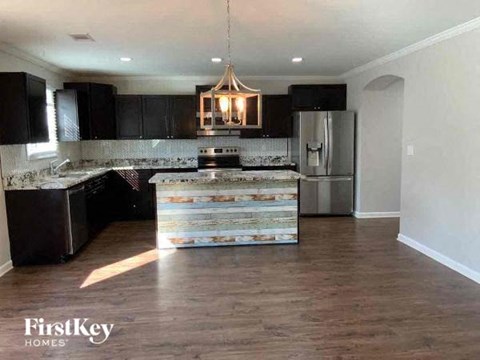 A kitchen with a wooden floor and a patterned tile backsplash.