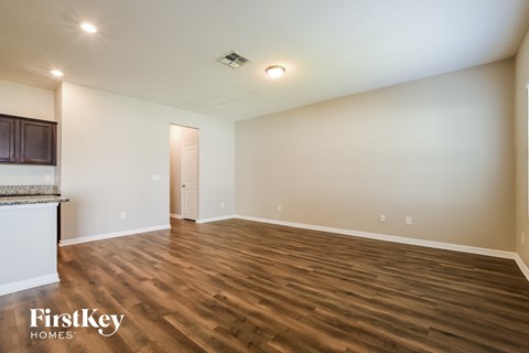 A spacious room with wooden flooring and a door in the background.