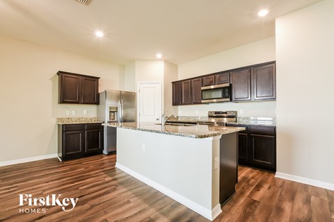 A kitchen with dark brown cabinets and a granite countertop.