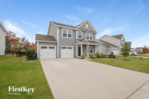 a gray house with white garage doors and a driveway