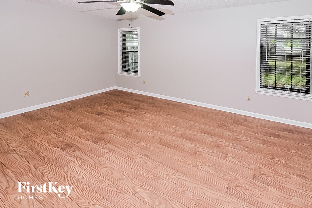 the living room after remodeling with wood flooring and a ceiling fan