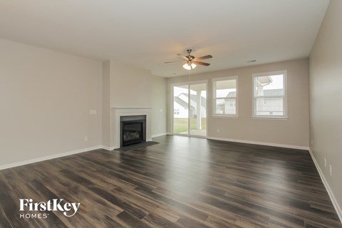A spacious living room with wood flooring and a fireplace.