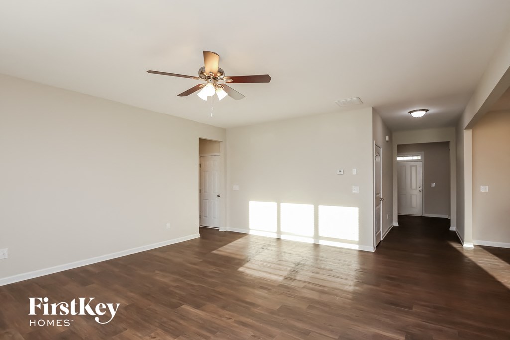 A spacious room with a ceiling fan and wooden flooring.