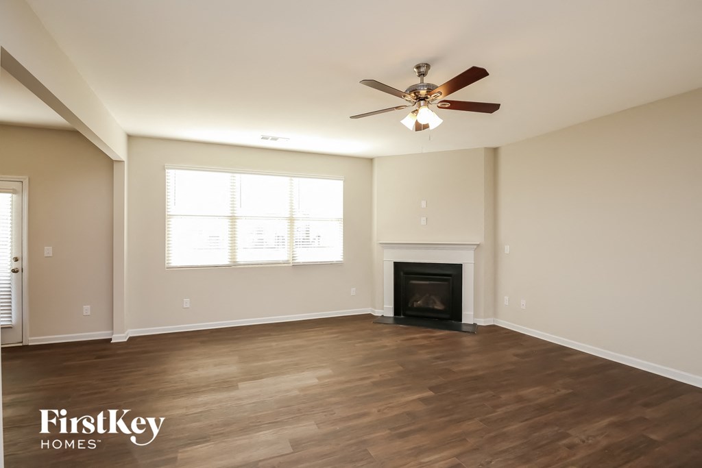 A spacious room with a fireplace and a ceiling fan.