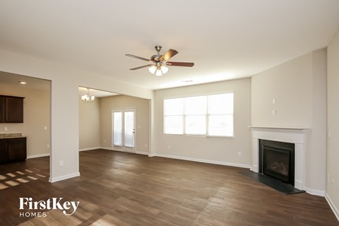 A spacious living room with a fireplace and a ceiling fan.
