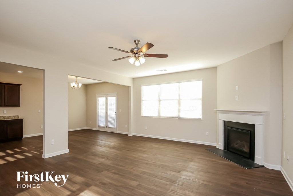 A spacious living room with a fireplace and a ceiling fan.