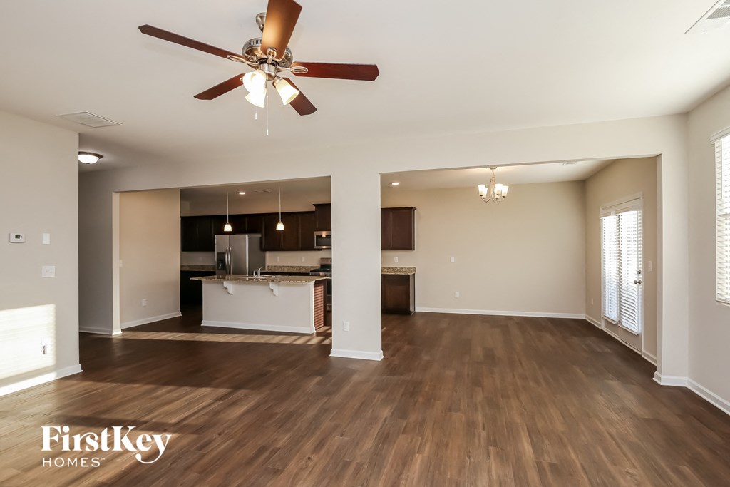 A spacious living room with a ceiling fan and hardwood floors.