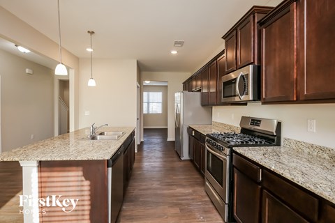 A kitchen with brown cabinets and a granite counter top.