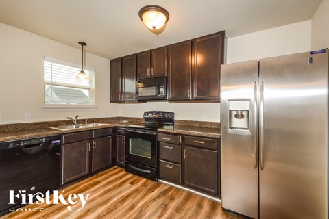 A kitchen with a stainless steel refrigerator and wooden floors.