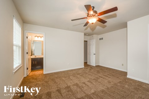 A spacious room with a ceiling fan and carpeted floor.