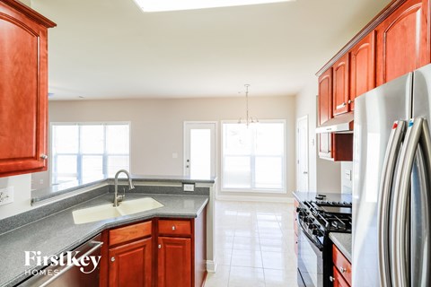 A kitchen with red cabinets and a stainless steel refrigerator.
