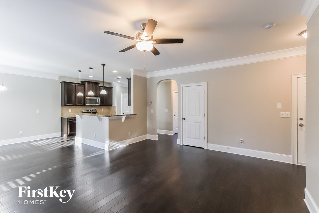 A spacious room with a ceiling fan and wooden flooring.