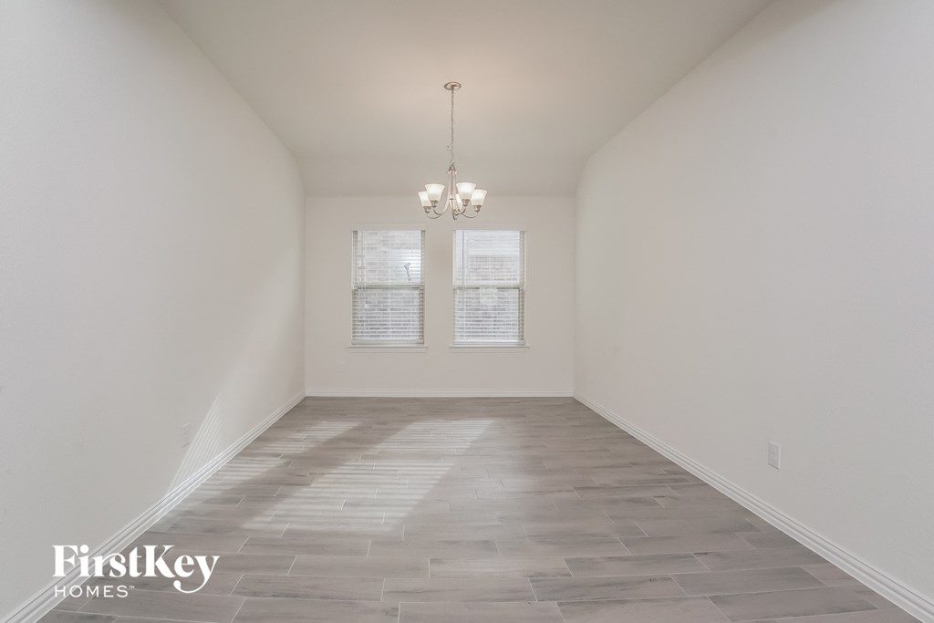an empty room with a chandelier and two windows