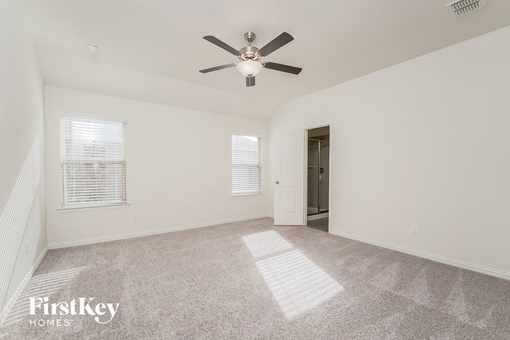 a spacious living room with carpet and a ceiling fan