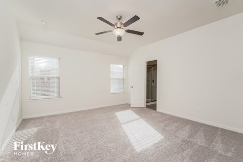 a spacious living room with carpet and a ceiling fan