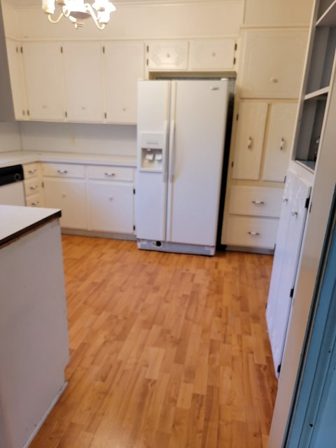 a kitchen with a wooden floor and white cabinets