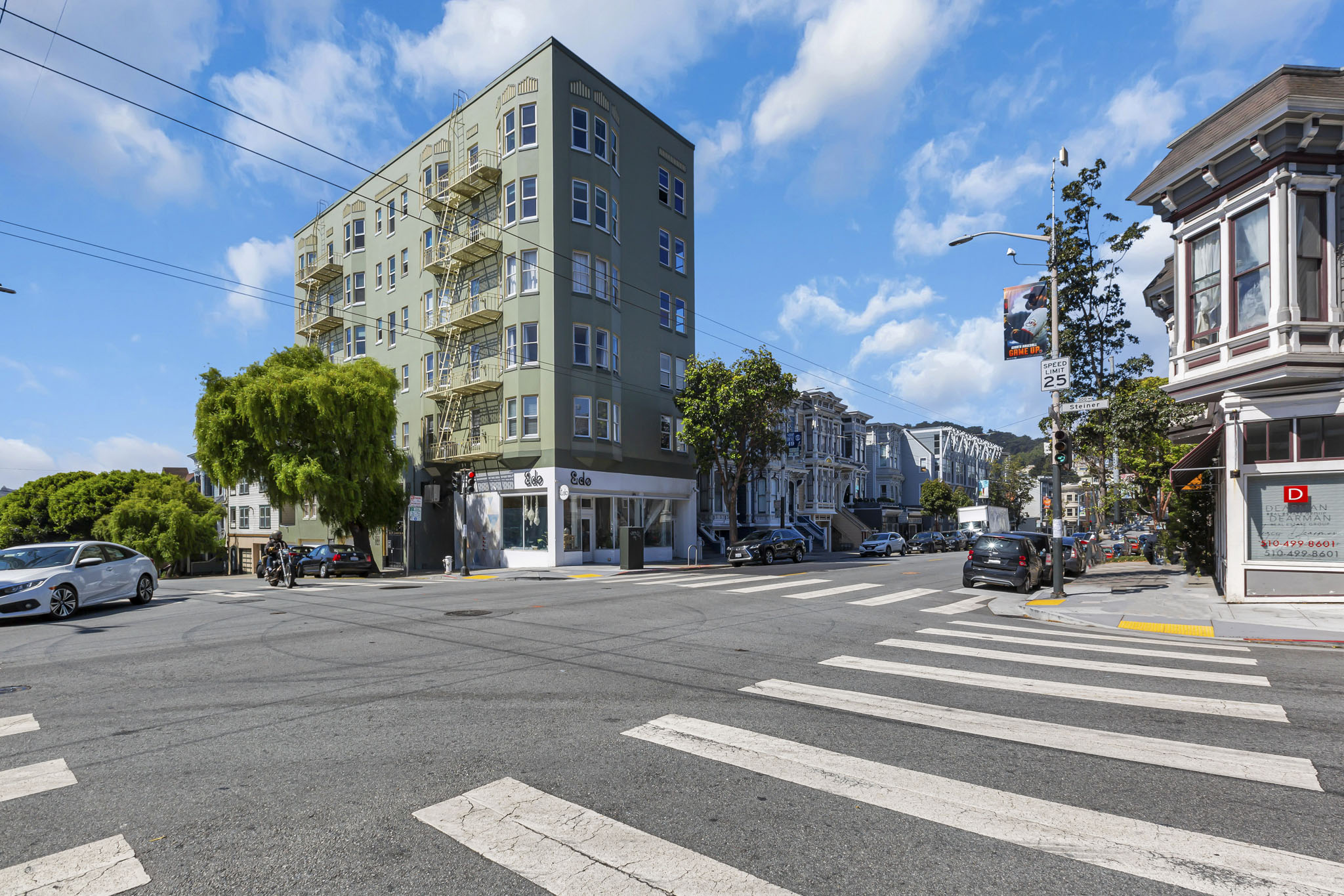 A street view with a white car and a tall building.