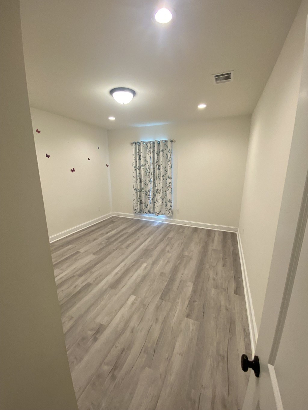 the upstairs living room has hardwood floors and a window with a curtain