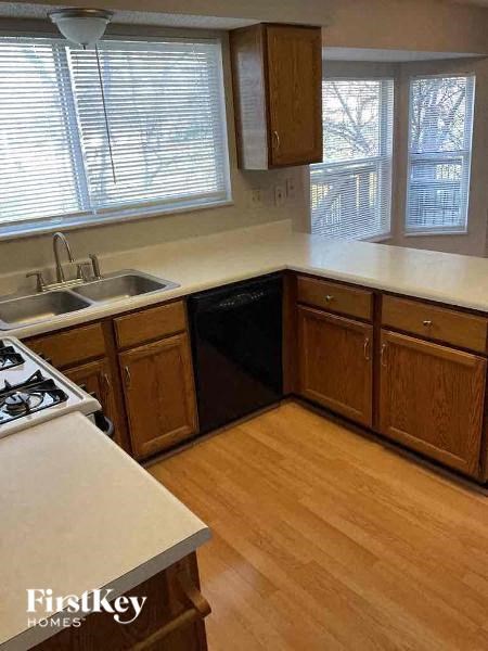 A kitchen with wooden cabinets and a black dishwasher.