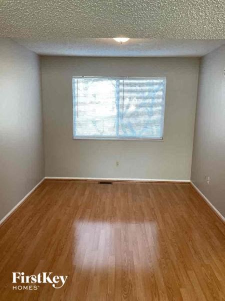 A room with wooden flooring and a window with blinds.
