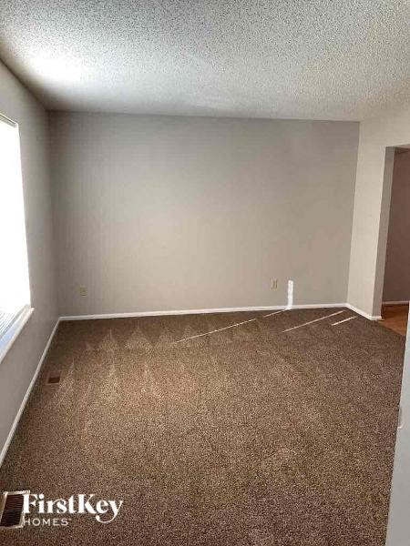 A room with a carpeted floor and a door on the right side.