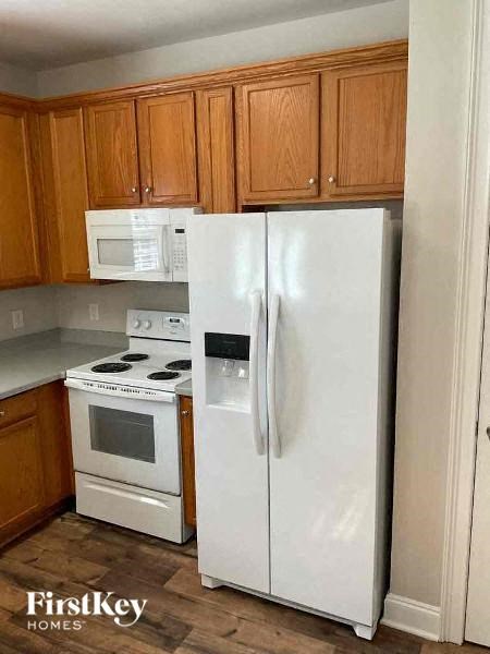 A white refrigerator stands in a kitchen with wooden cabinets.