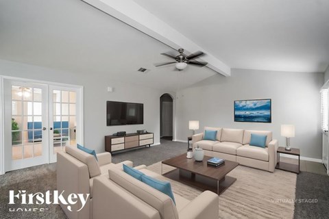A living room with a flat screen TV and a large painting on the wall.