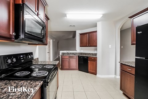 A kitchen with a black stove top oven and black microwave above it.