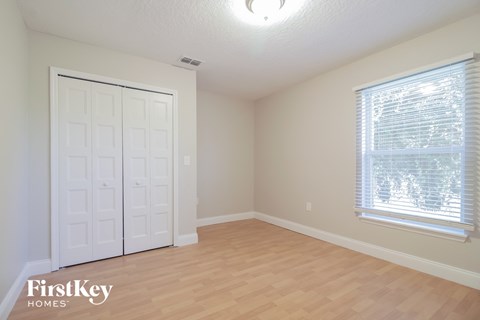 a bedroom with a wood floor and a door and a window