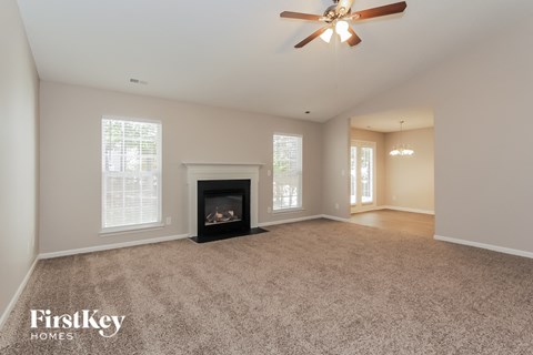 an empty living room with a fireplace and a ceiling fan