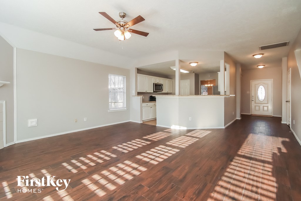 A spacious room with wooden floors and a ceiling fan.