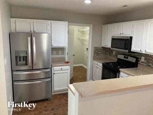 A kitchen with a stainless steel refrigerator and white cabinets.