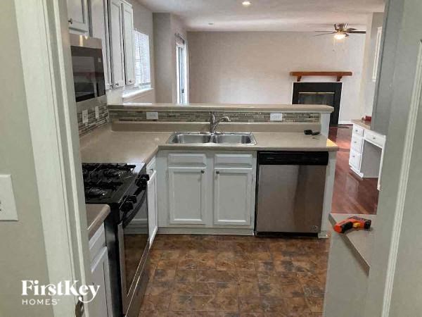 A kitchen with a stove top oven, sink, and a refrigerator.