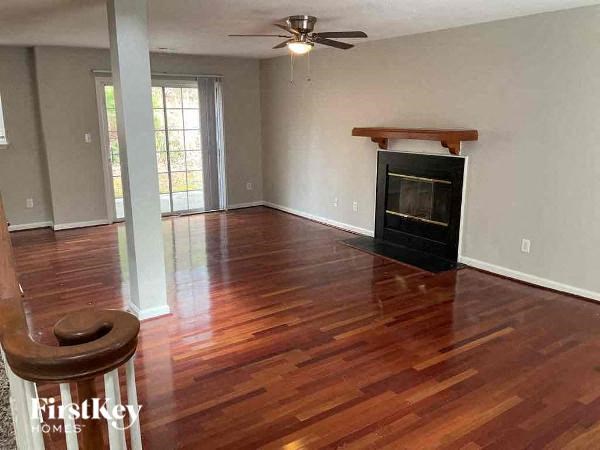 A wood floor in a room with a fireplace and a fan.