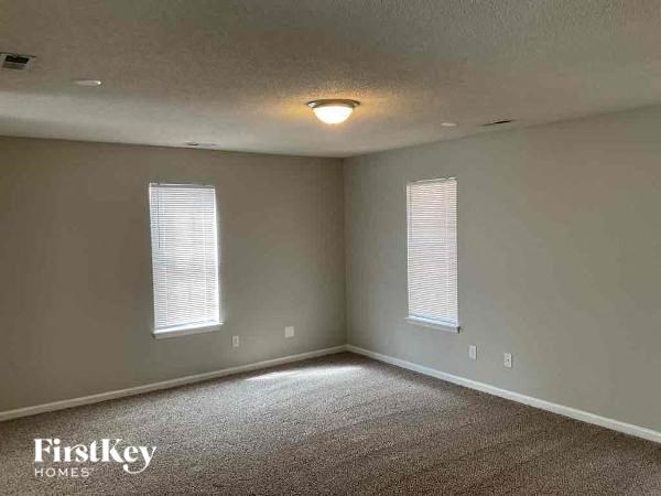 A room with two windows and a carpeted floor.