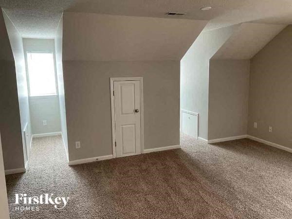 A carpeted room with a door and a window.