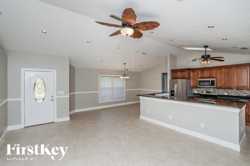 an empty kitchen and living room with a ceiling fan