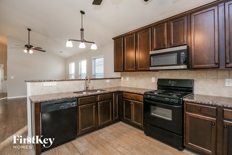 A kitchen with dark brown cabinets and black appliances.