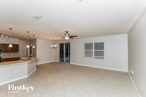 an empty living room and kitchen with a ceiling fan