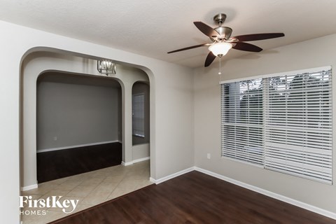 an empty living room with a large window and a ceiling fan