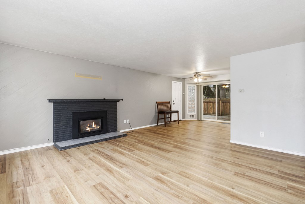 the living room of a house with a fireplace and wooden floors