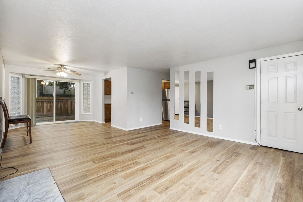 the living room and dining room of an empty house with white walls and wood floors