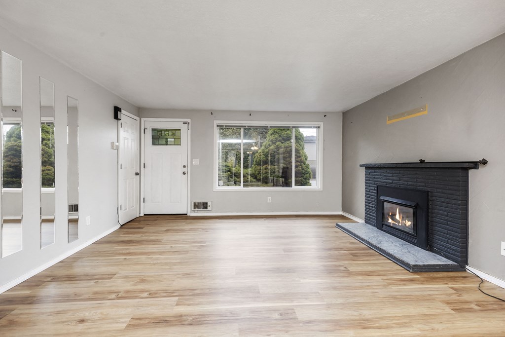 an empty living room with a fireplace and a window