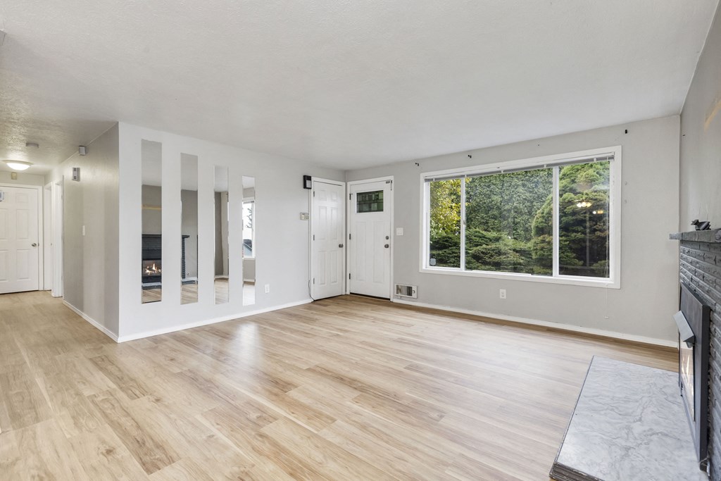 an empty living room with a fireplace and a large window