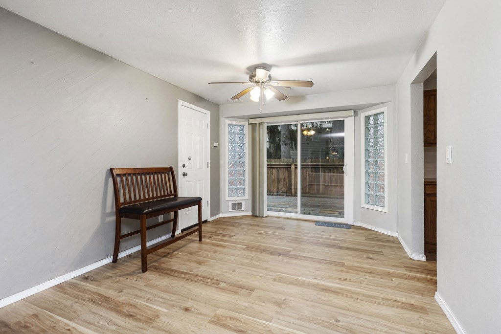 an empty living room with a chair and a ceiling fan
