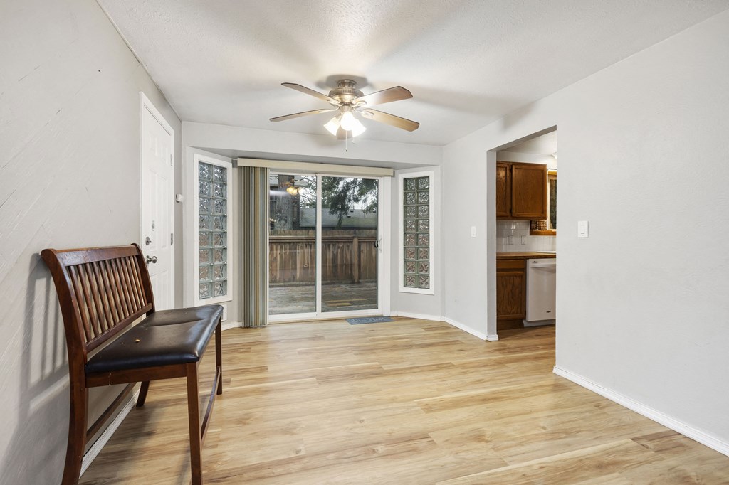 an empty living room with a ceiling fan and a sliding glass door