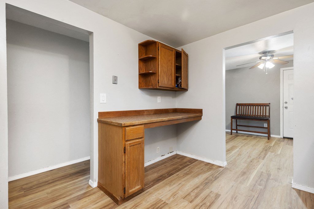 an empty living room with a wooden desk in the corner