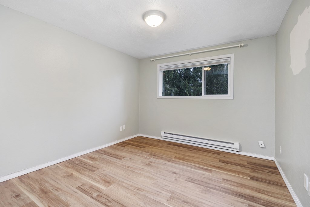 an empty room with wood flooring and a window