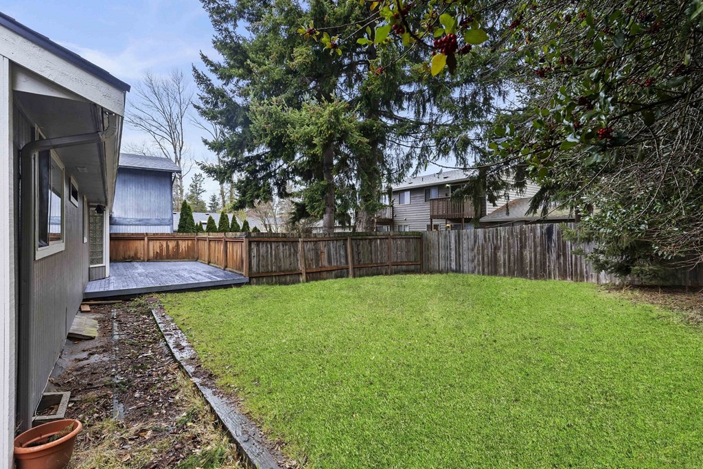a backyard with a wooden fence and a yard with grass and a deck