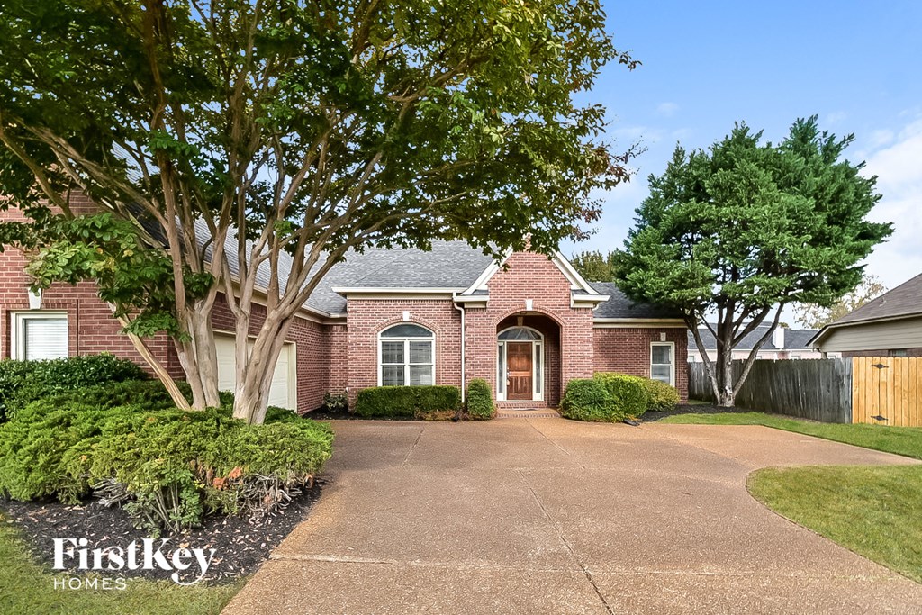 A brick house with a driveway in front of it.